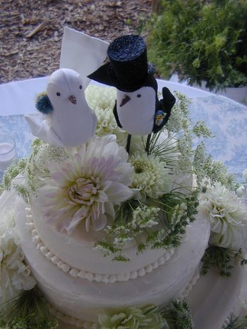 Edible flowers and bird cake topper on a wedding cake