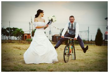 bride with white bouquet and groom on bike