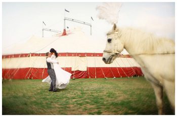 bride and groom hug next to a circus tent