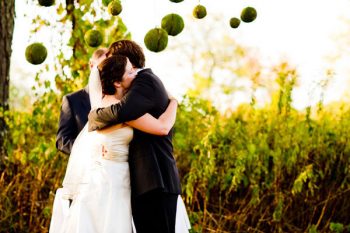 bride and groom hug with moss balls in the background