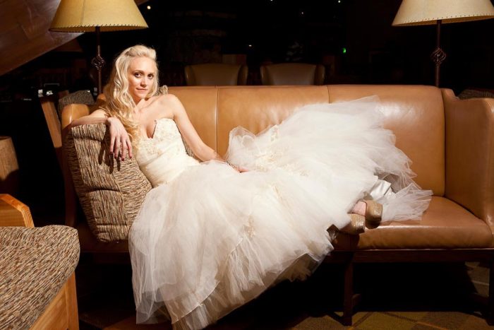 Beautiful bride lounges on a leather sofa