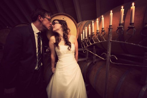 Bride and a groom kiss in a wine cellar