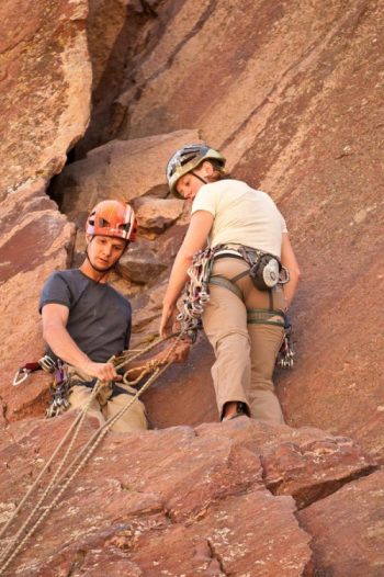 engaged rock climbing couple at the top of a pitch