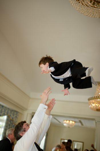 ring bearer gets thrown into the air by a wedding guest