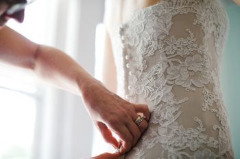 bride buttoning her lace gown
