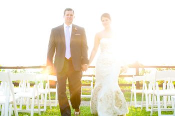 Bride and groom holding hands in a sun flare