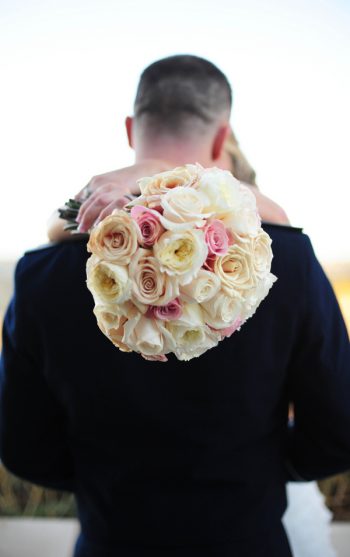 bride holding pink and white rose bouquet kisses her groom