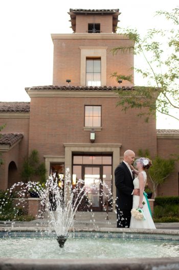 bride and groom embrace near a fountain