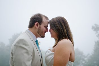 bride and groom nuzzle in the mist