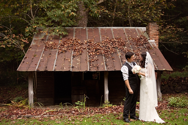 Bride and groom pose in front of a rustic mountain shed in North Carolina
