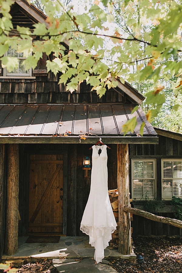 lace wedding gown hanging from a rustic cabin