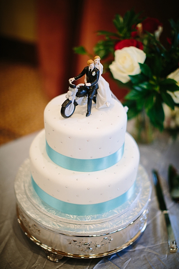 wedding cake with turquoise ribbon and motorcycle cake topper