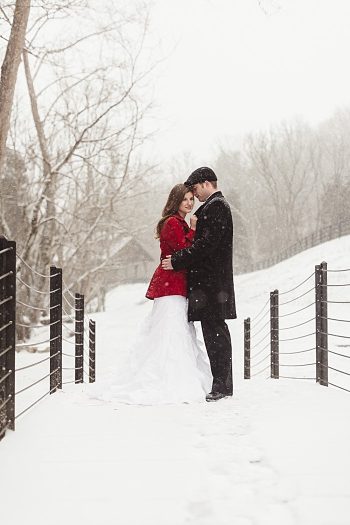 bride in red coat with groom on a bridge