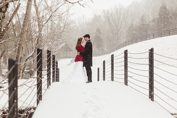 bride in red coat with groom on a bridge