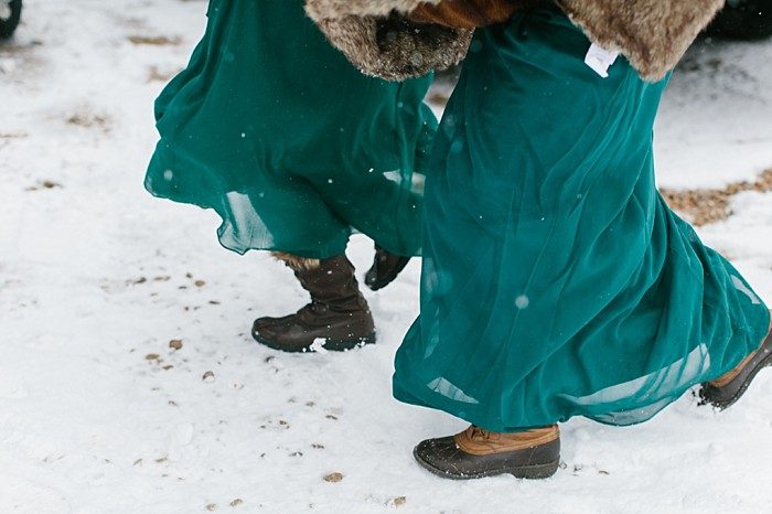 Bridesmaid in a teal dress and winter boots standing in the snow