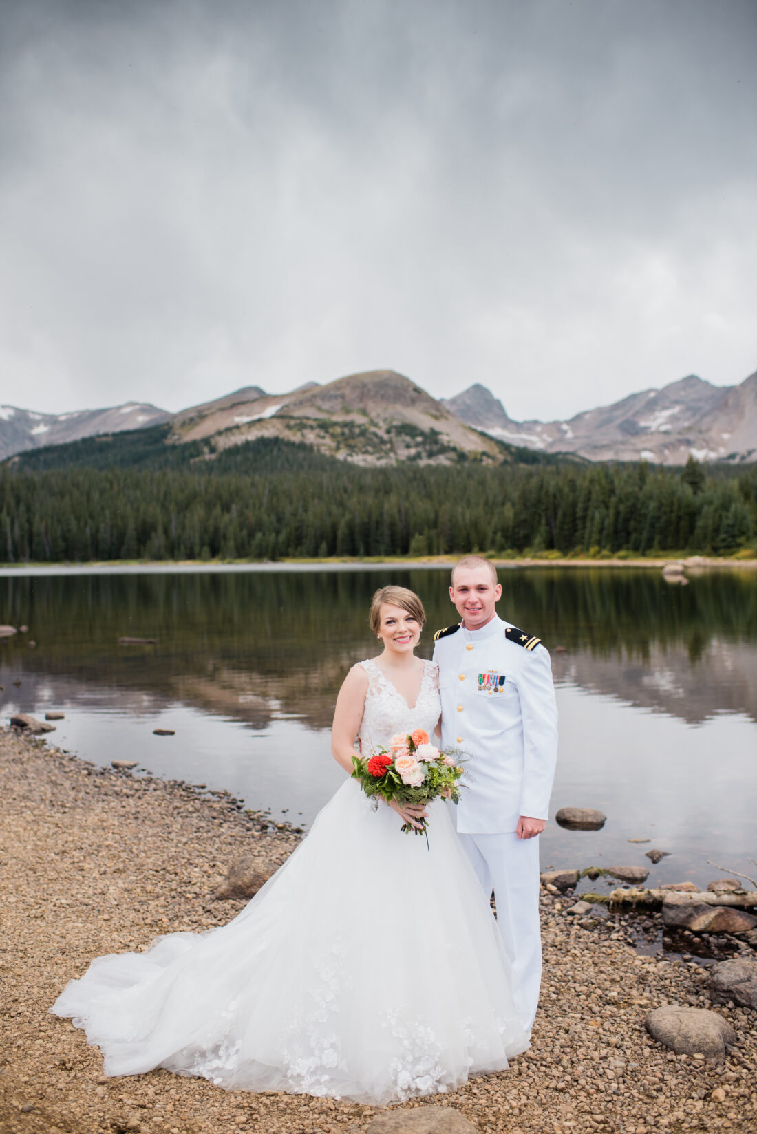 bride and groom by the lake with mountains in the background