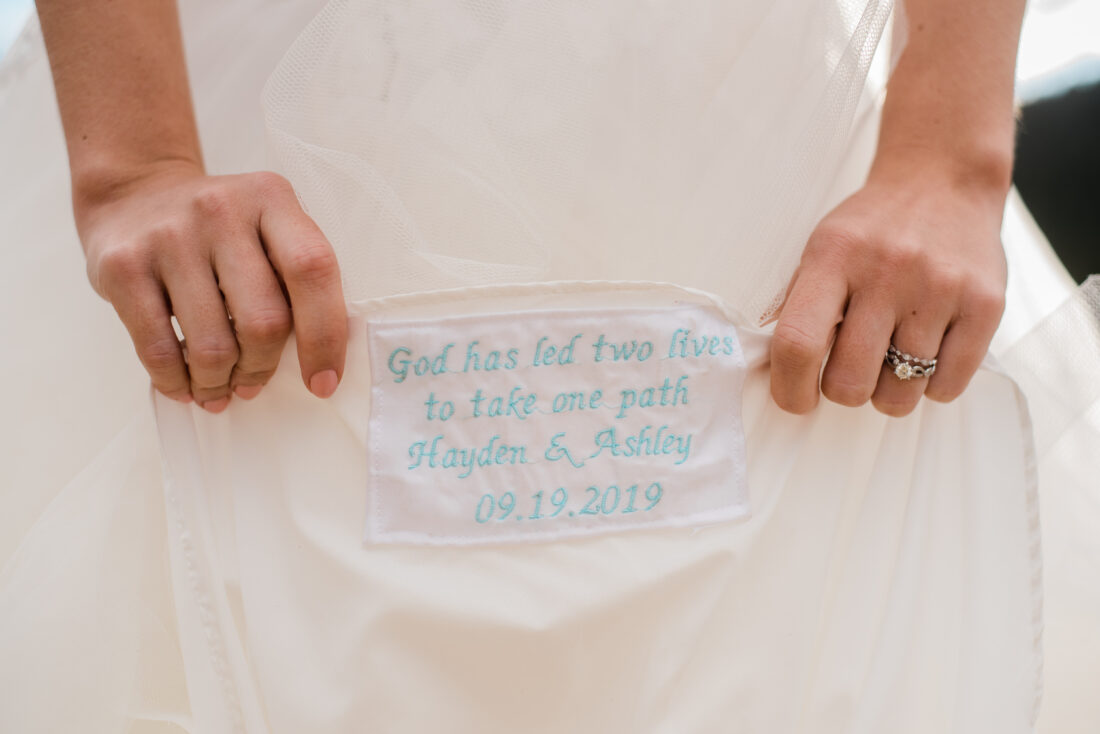 bride showing blue embroidered message on dress