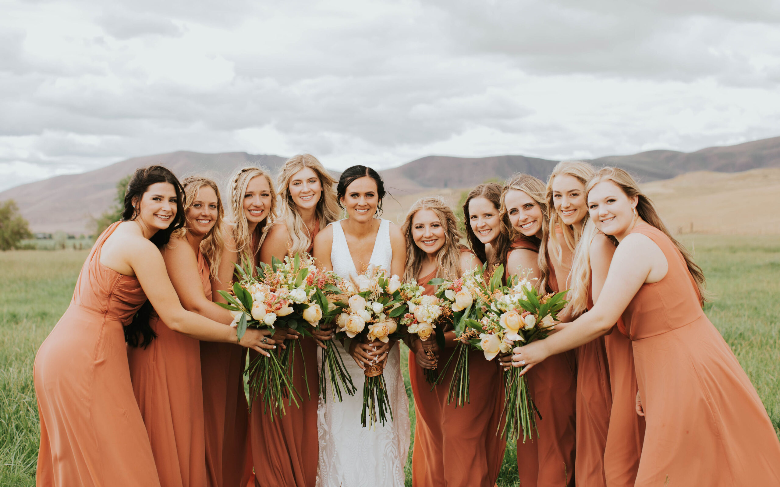 bride and bridesmaids in burnt orange bridesmaid dresses holding bouquets