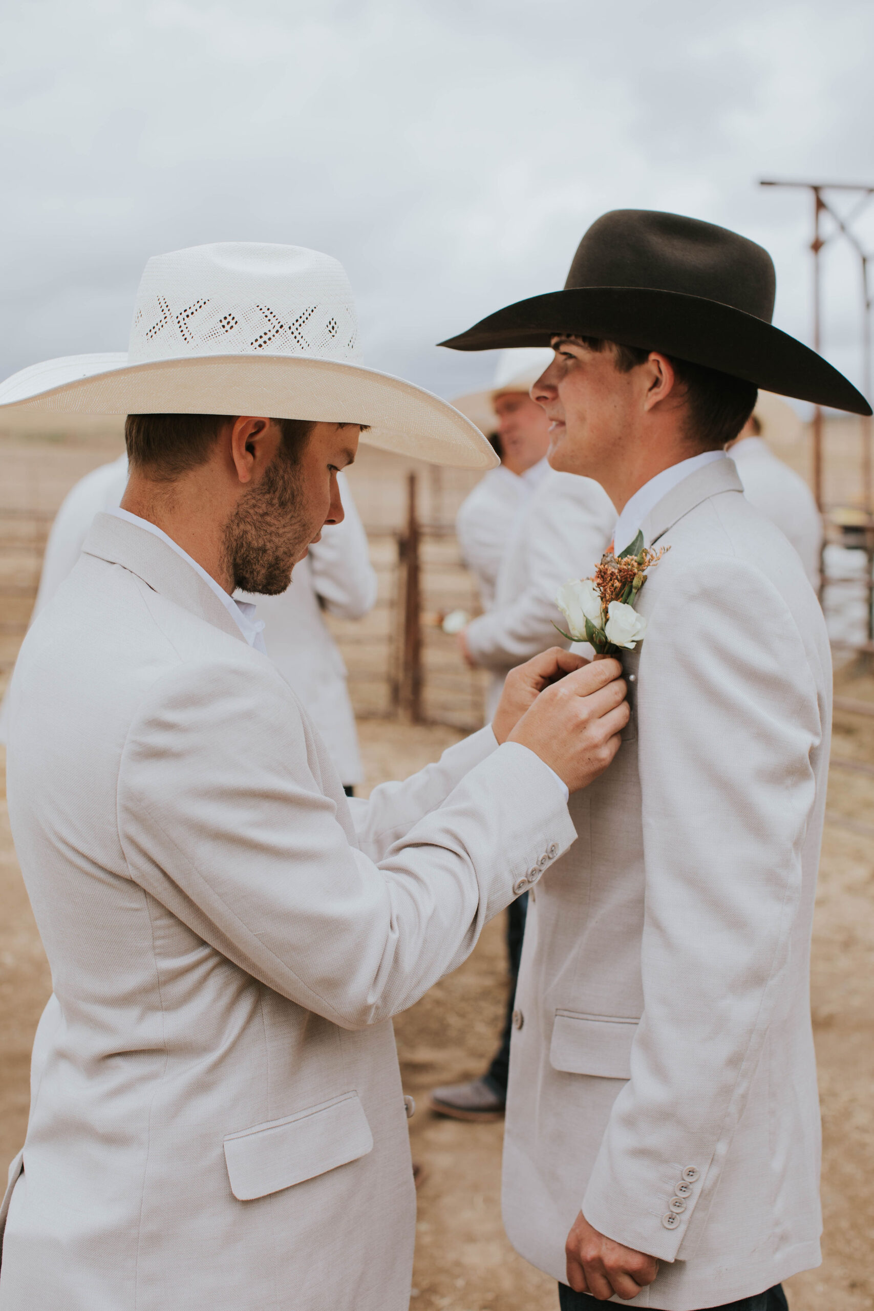 groom in chocolate cowboy hat getting boutinere put on.
