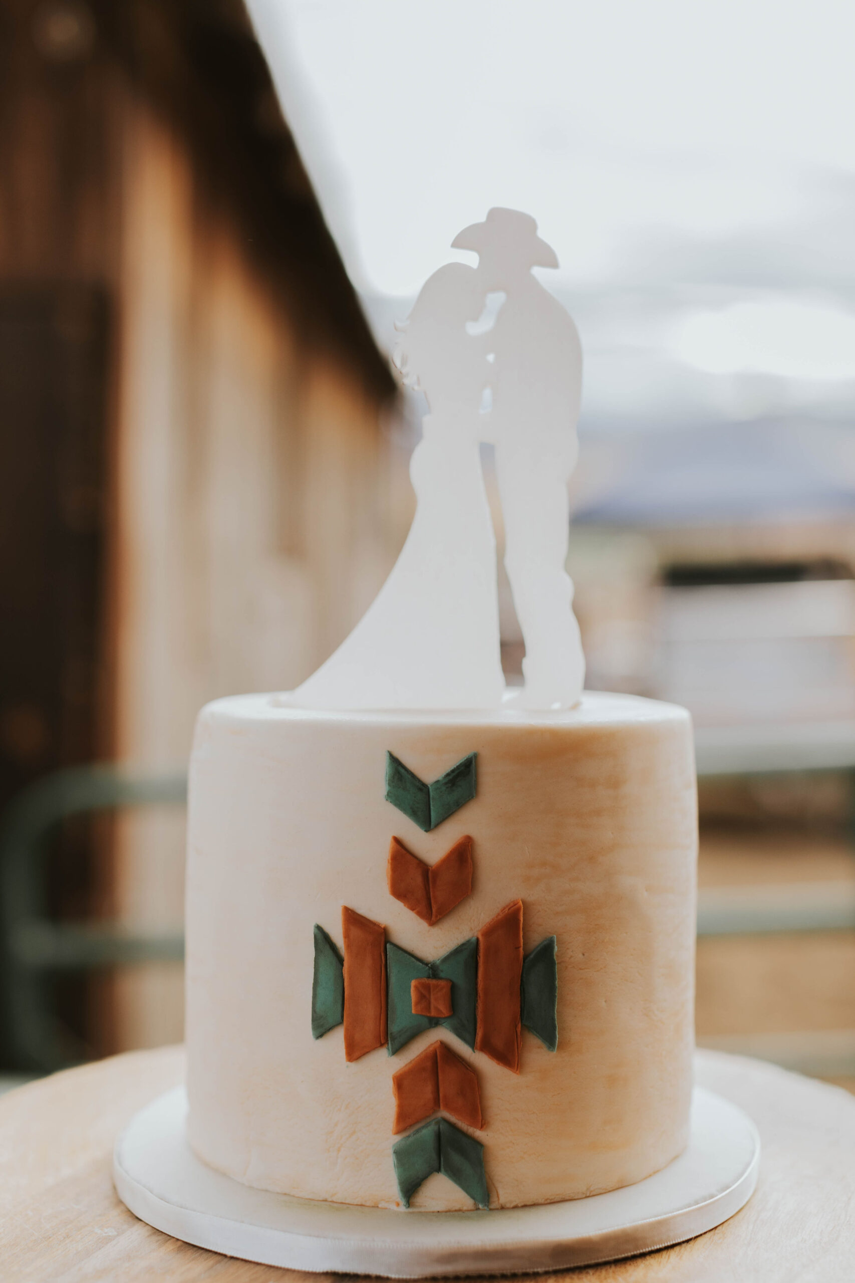 wedding cake with bride and groom with cowboy hat and southwestern accents in a rustic orange wedding