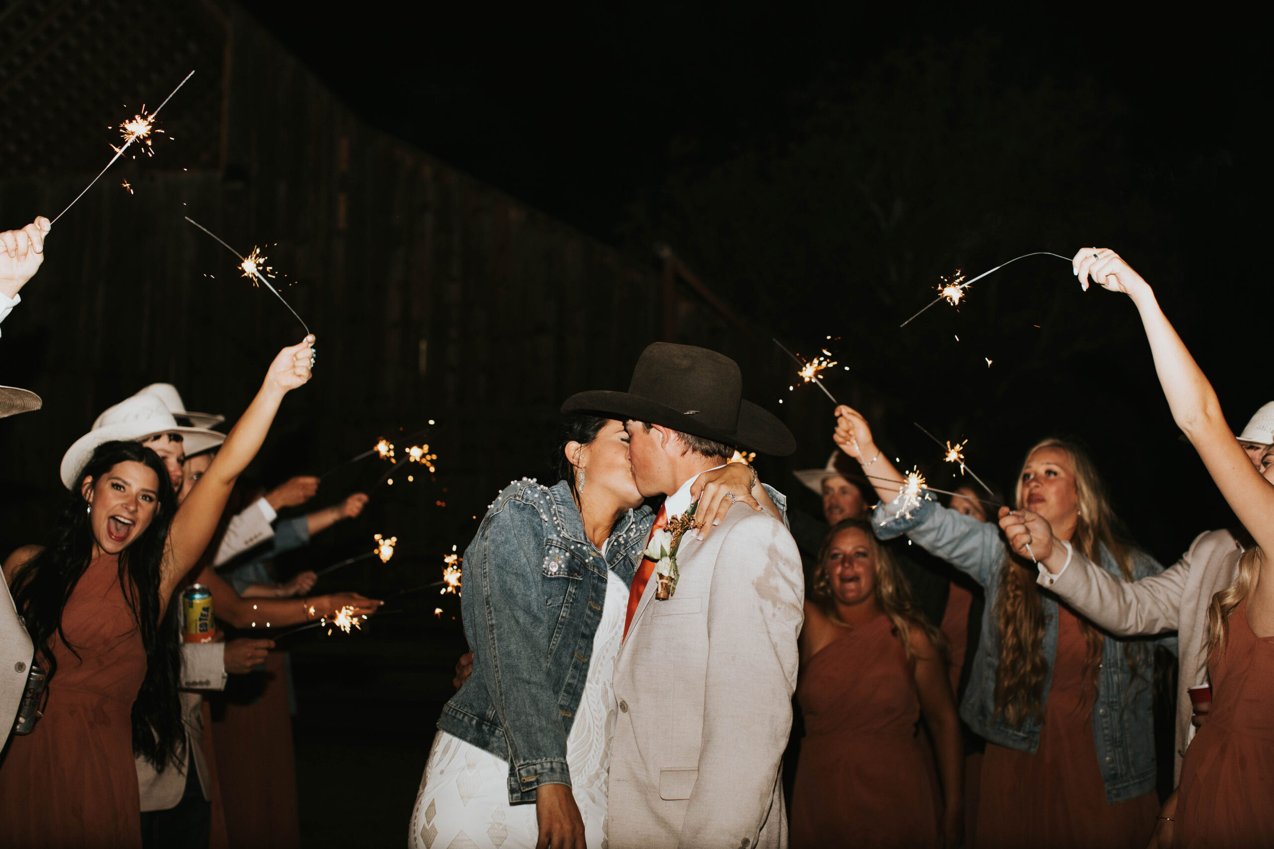 bride and groom leaving their wedding with sparklers in a rustic orange mountain wedding