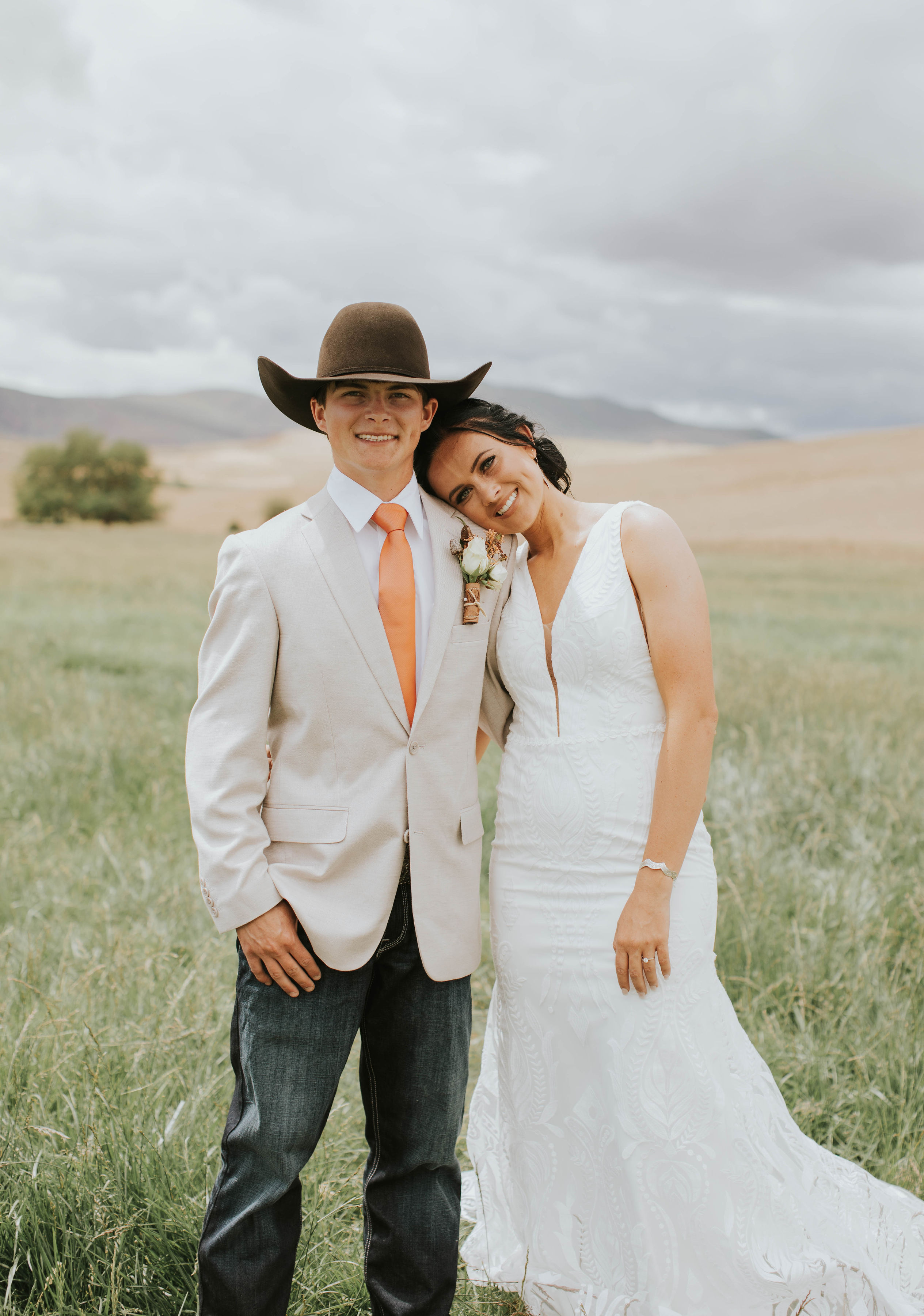 bride and groom with chocolate cowboy hat hugging at their rustic orange mountain wedding