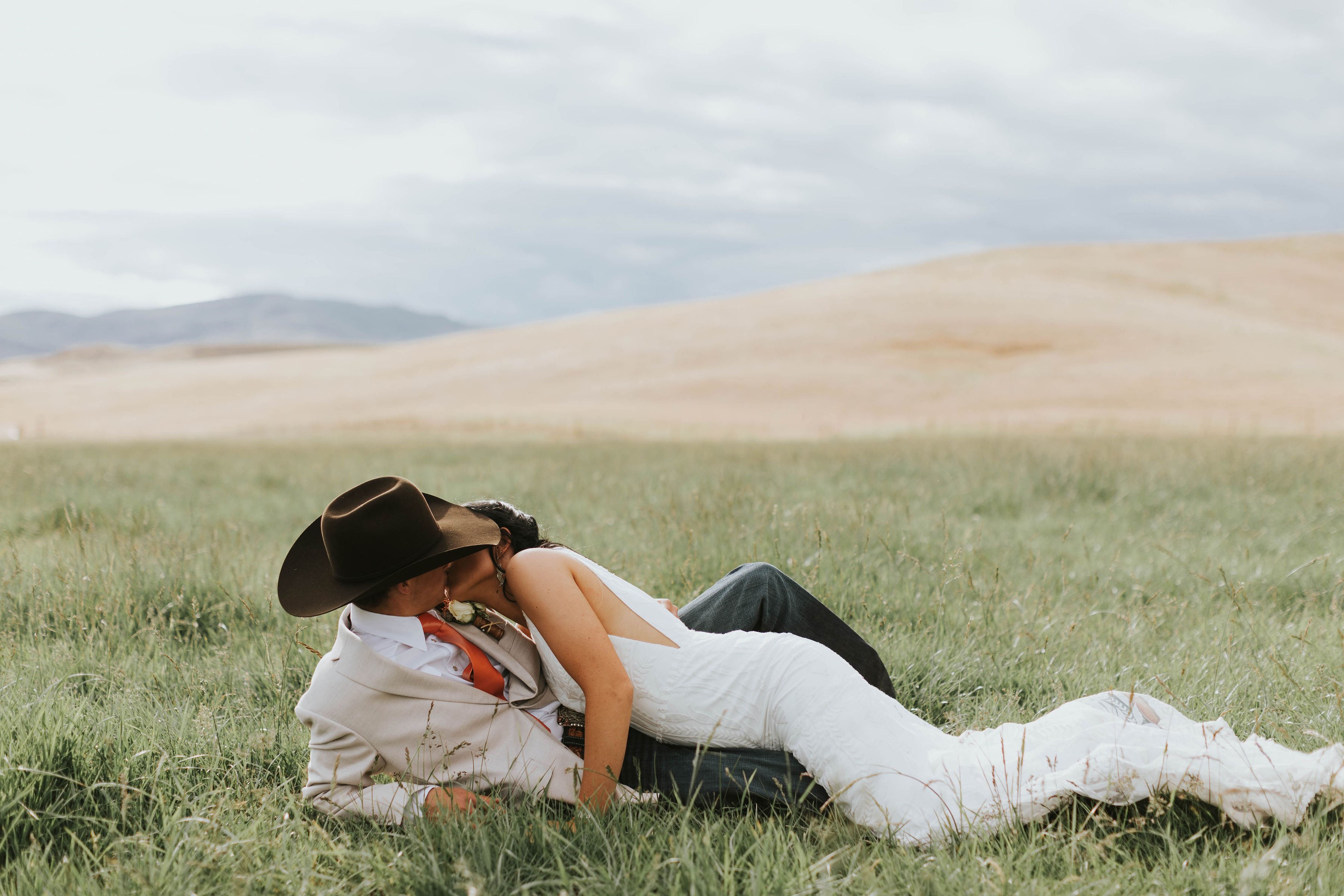 bride and groom with chocolate cowboy hat kissing at their rustic orange mountain wedding